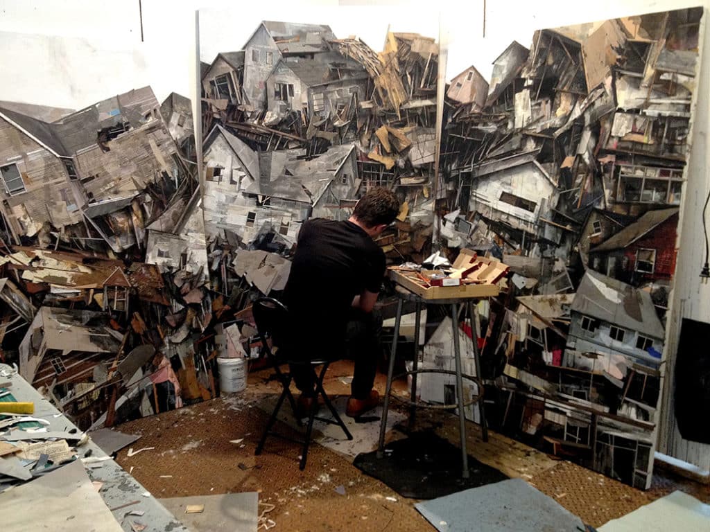 A man painting fragmented houses on a wall